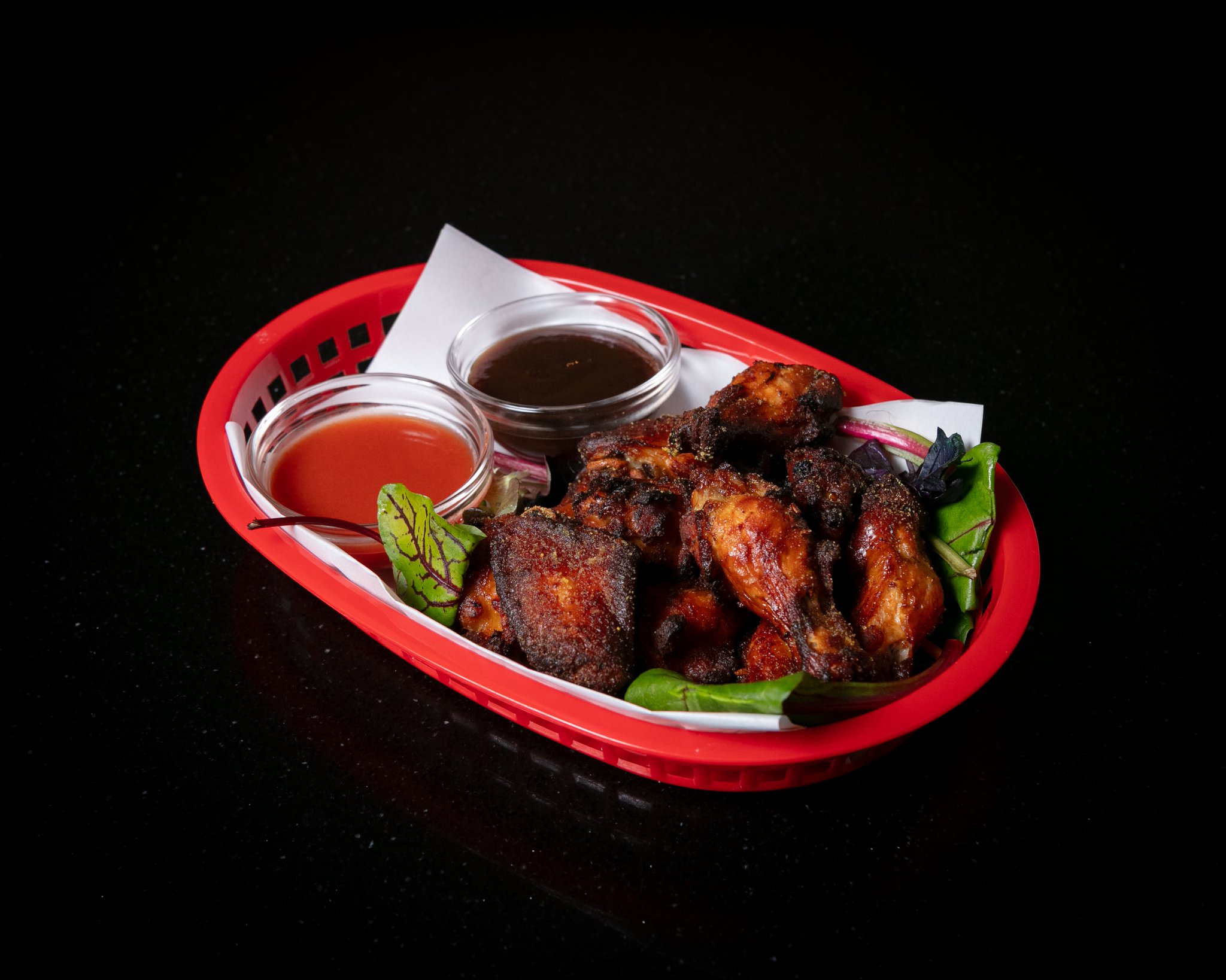 Basket of glazed chicken wings with dipping sauces