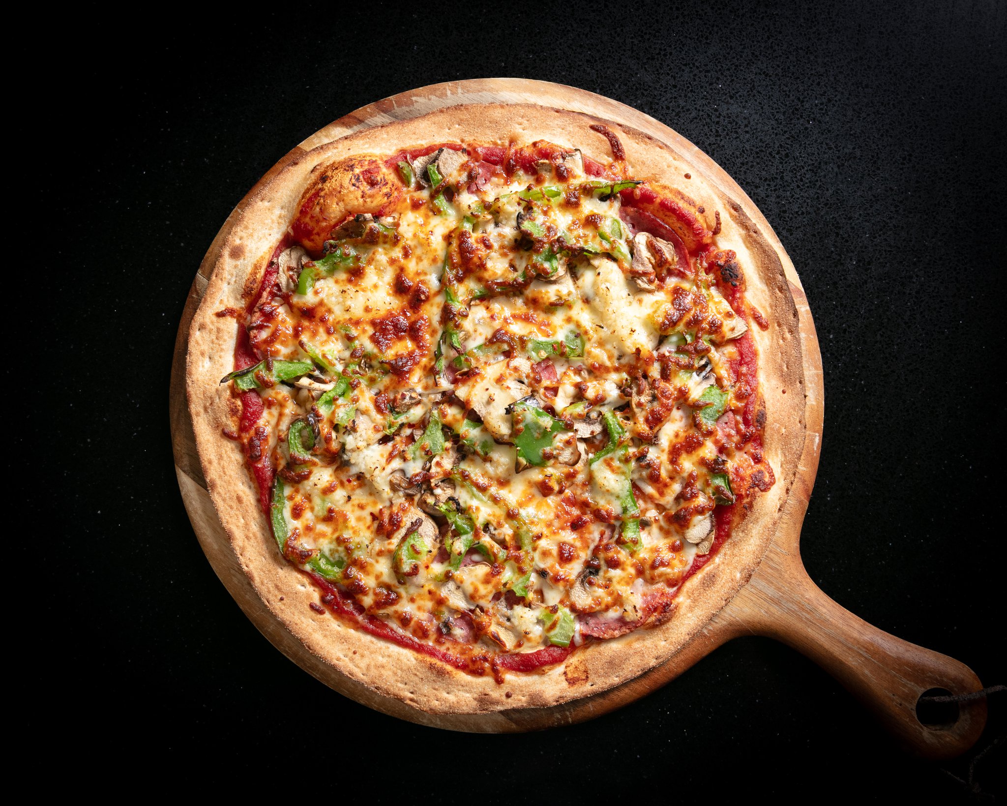 Salami supreme pizza with mushroom and capsicum on a wooden board