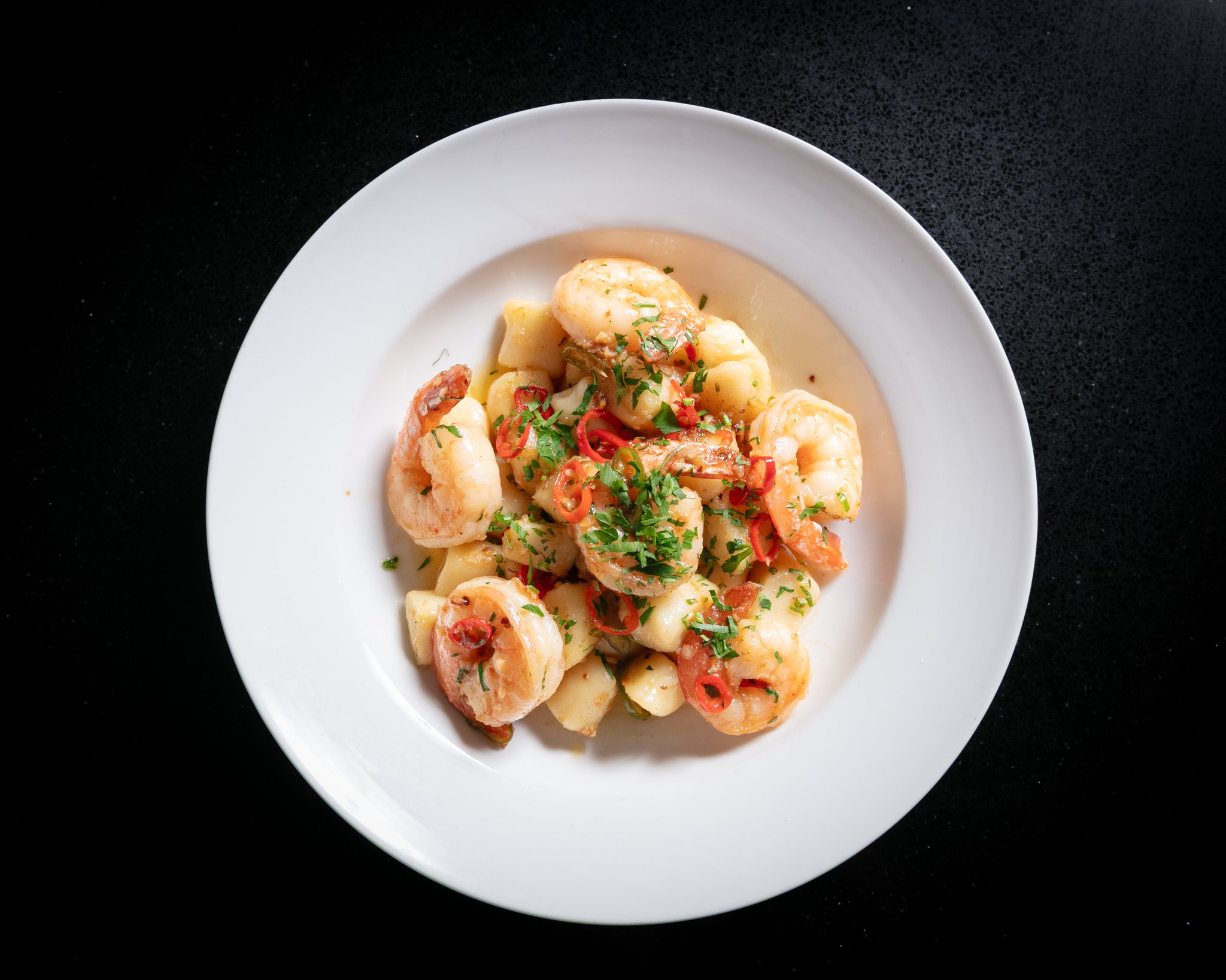 Garlic prawns tossed with herbs in a white bowl