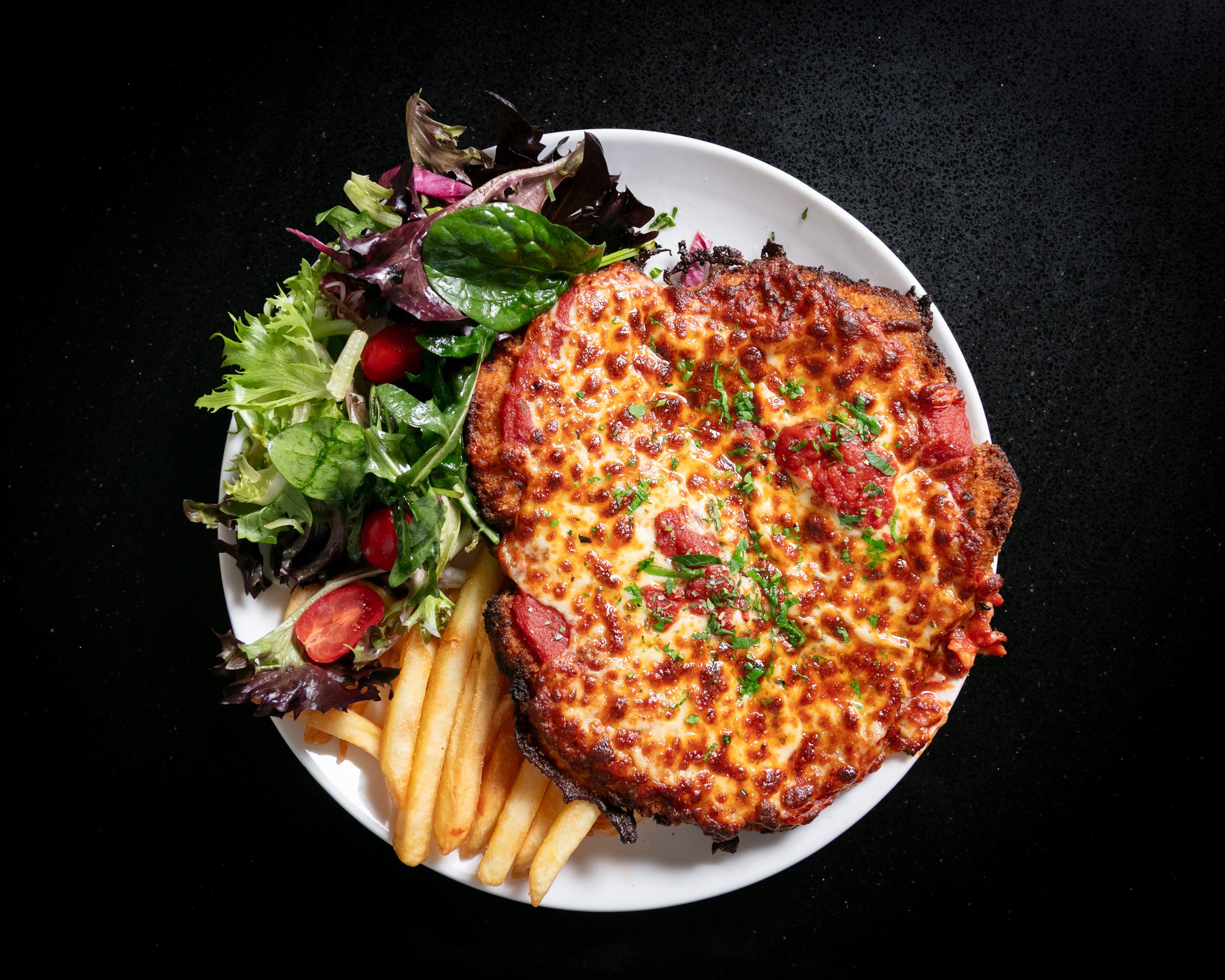Chicken parmigiana with melted cheese, chips and garden salad