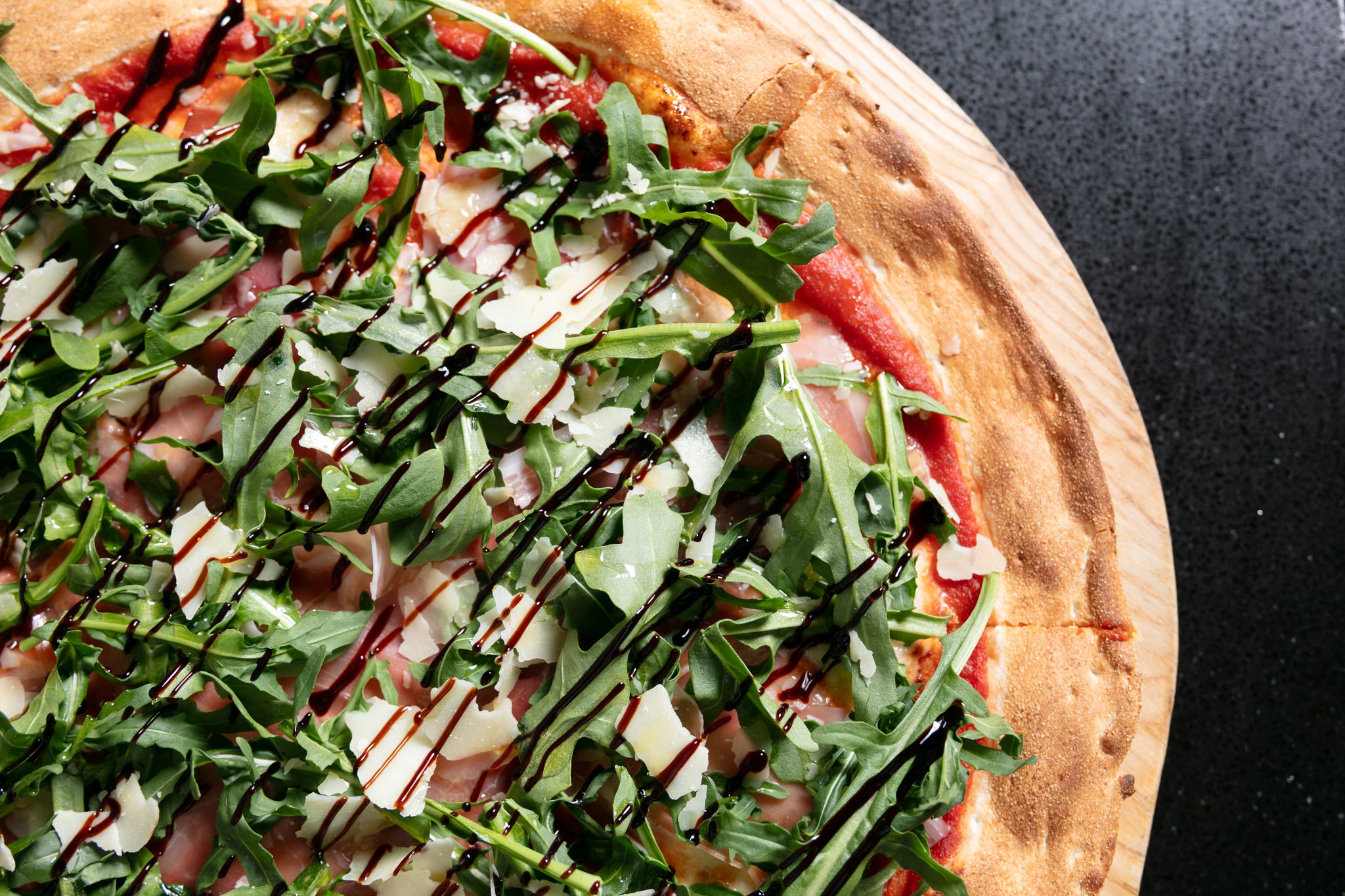 Close-up of a pizza topped with fresh rocket and balsamic glaze