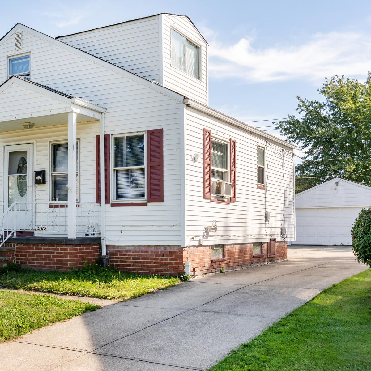 White cottage with a red door and front lawn