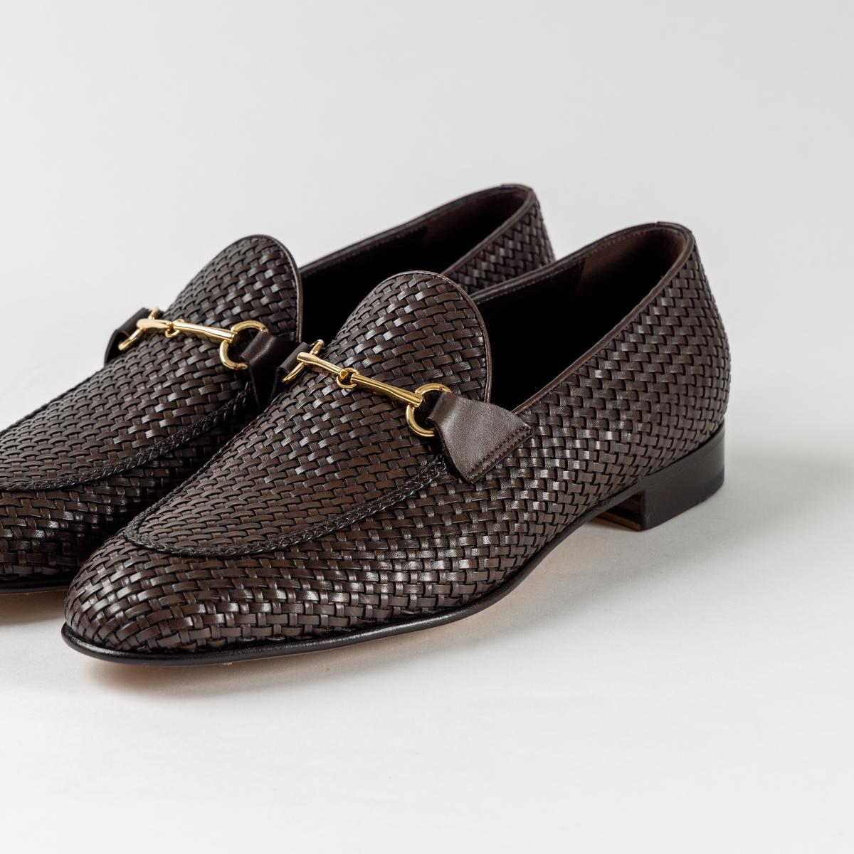Pair of woven leather loafers with horsebit detail on a white surface