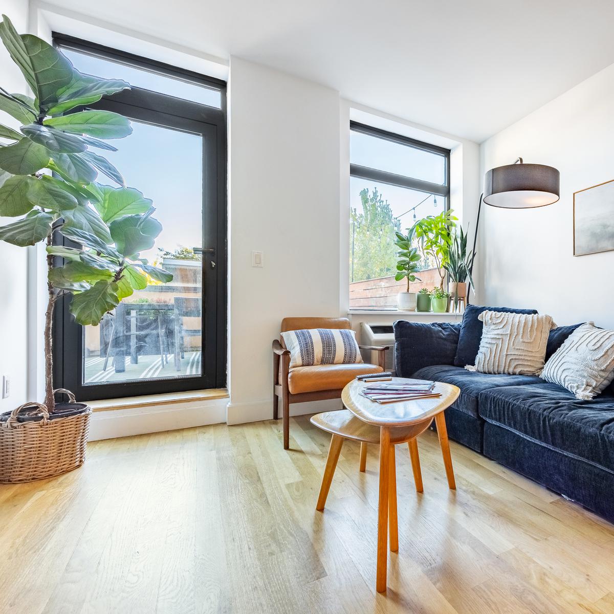 Bright living room with a navy sofa, round wood coffee table and floor-to-ceiling windows