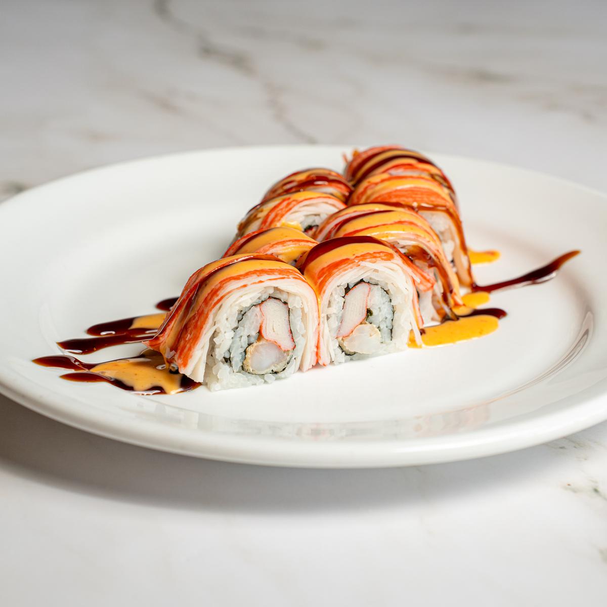 Sushi roll plated on white with a drizzle of sauce