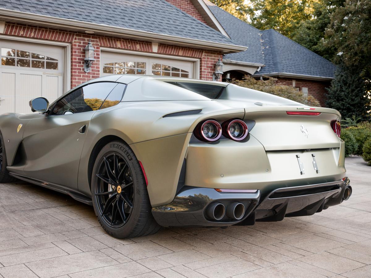 Matte olive Ferrari 812 Superfast, rear three-quarter view on a brick driveway