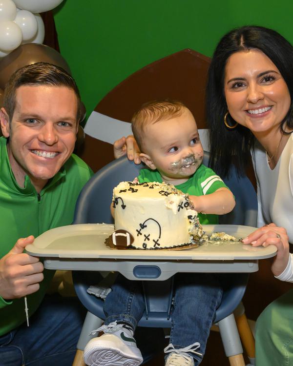 Parents with a baby and a smash cake at a first birthday