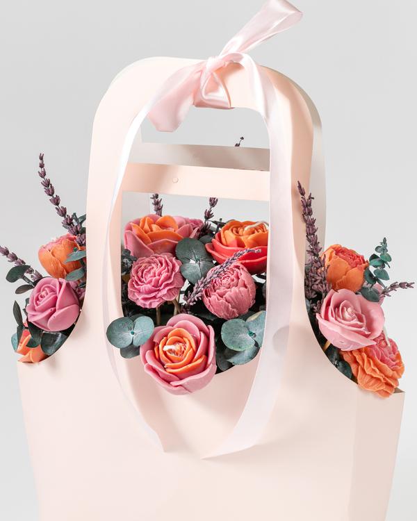 A bouquet of pink and peach roses in a pale pink gift bag