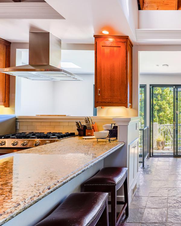 A bright kitchen with wooden cabinets and a granite breakfast bar