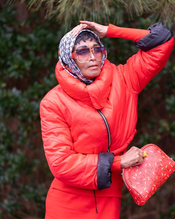A model in a red puffer coat and headscarf holding a red handbag
