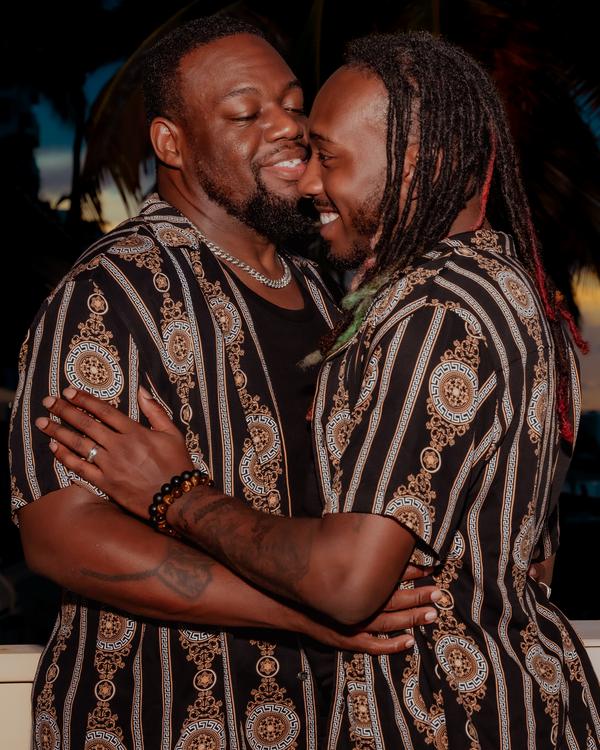 Two men in matching shirts embracing and smiling