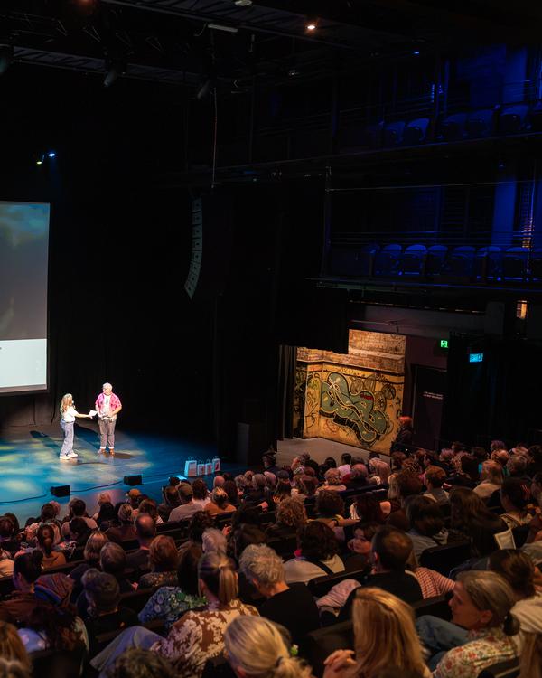 A full theatre audience watching speakers on stage