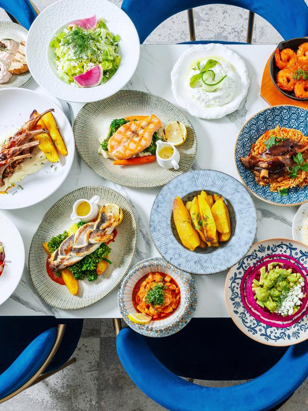 Overhead view of a table set with colourful plated dishes on blue patterned plates