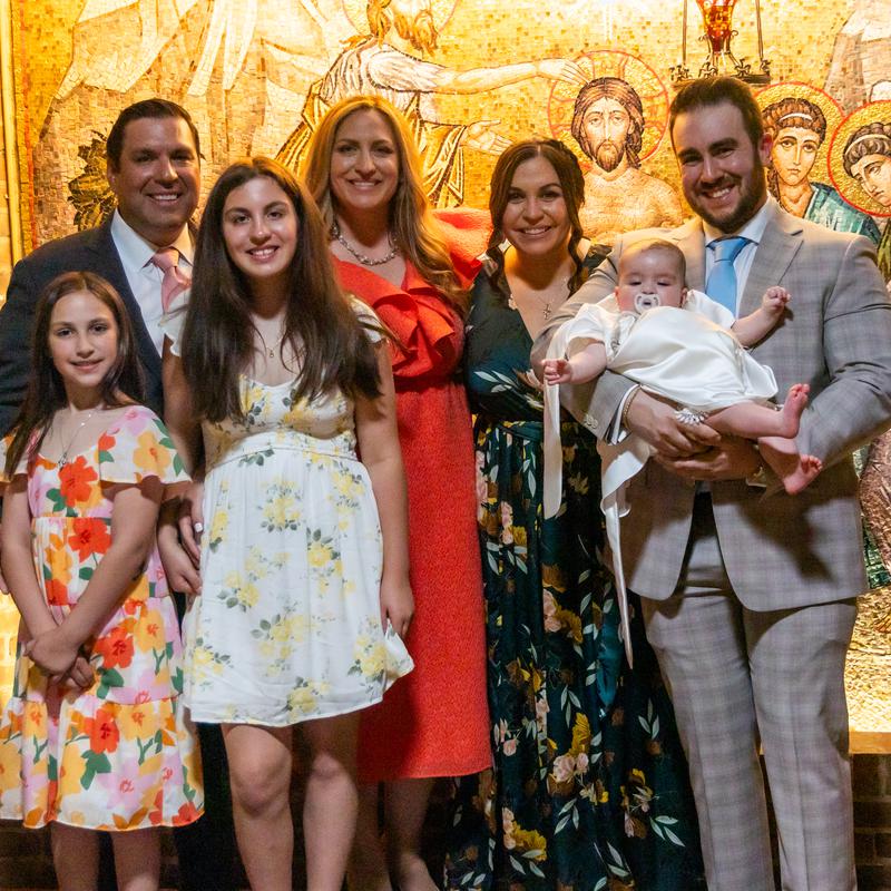 A family in their best clothes around a baby in a white christening gown