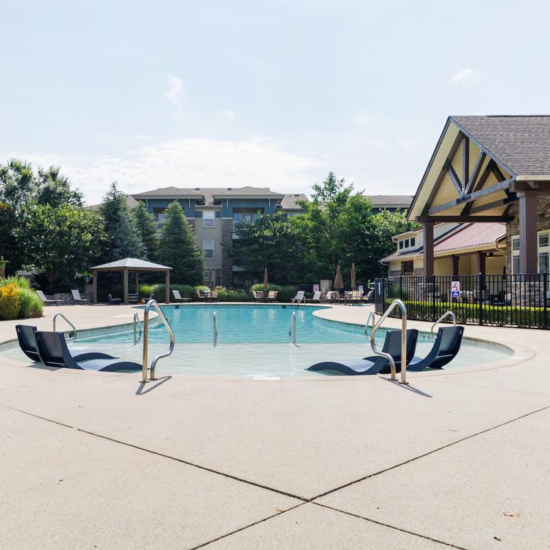 Resort-style outdoor pool with lounge chairs beside a clubhouse