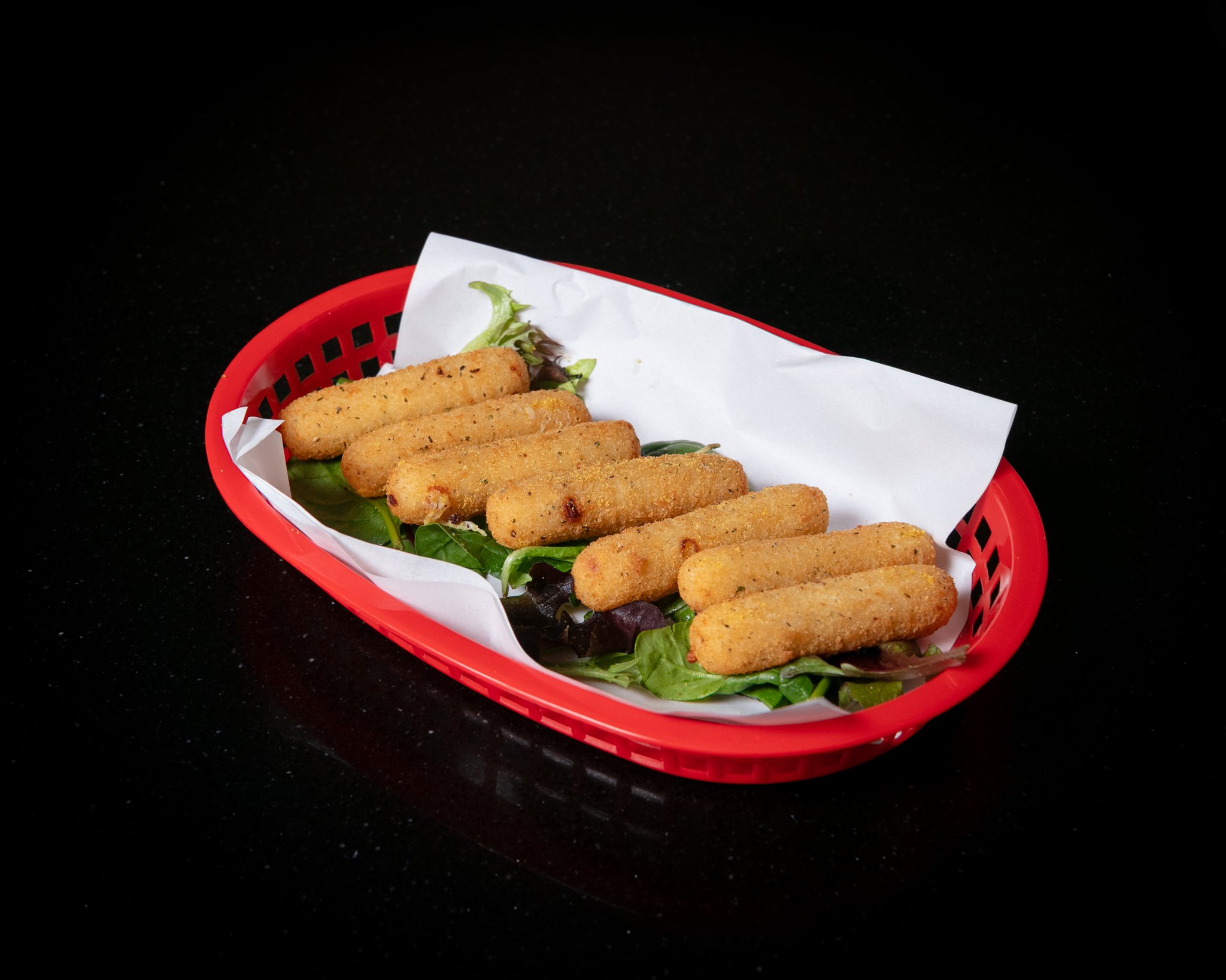 Golden mozzarella sticks in a red basket with dipping sauce